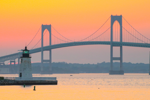 Newport Harbor Lighthouse and the Newport Bridge at sunset, located in the Narragansett Bay. Newport is an international sailing and tourist destination. New England coastal town. Travel, Vacation