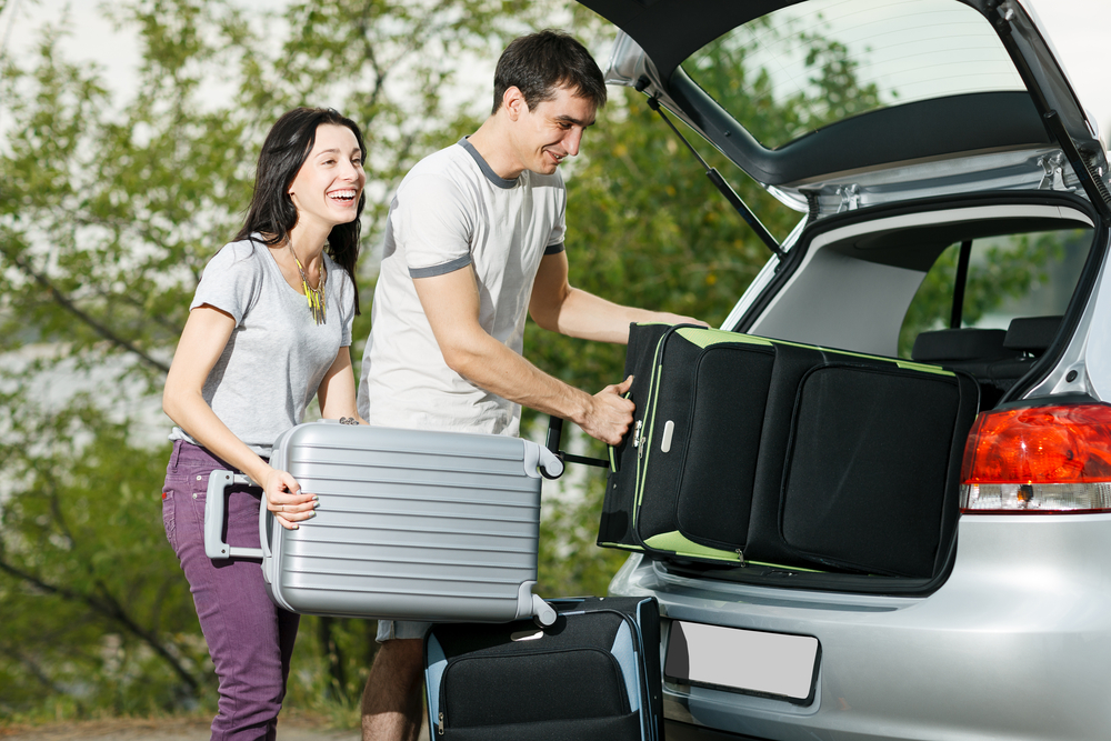 happy couple loading their belongings into a rental car,