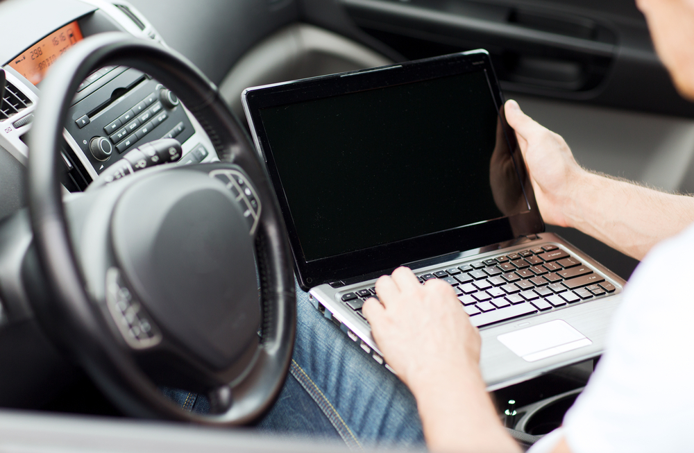 Business traveler working on a laptop in the car