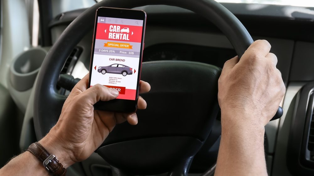 A person holding a smartphone with a car rental app open
