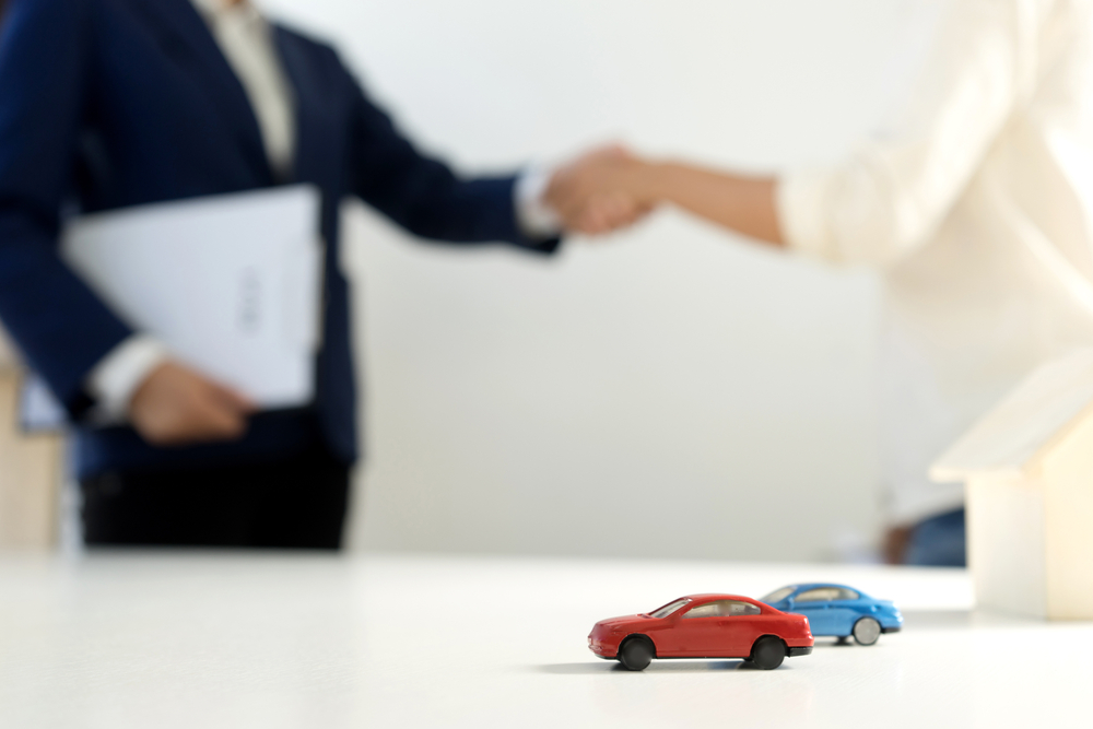 Customer and Agent Handshake at Car Rental Desk.